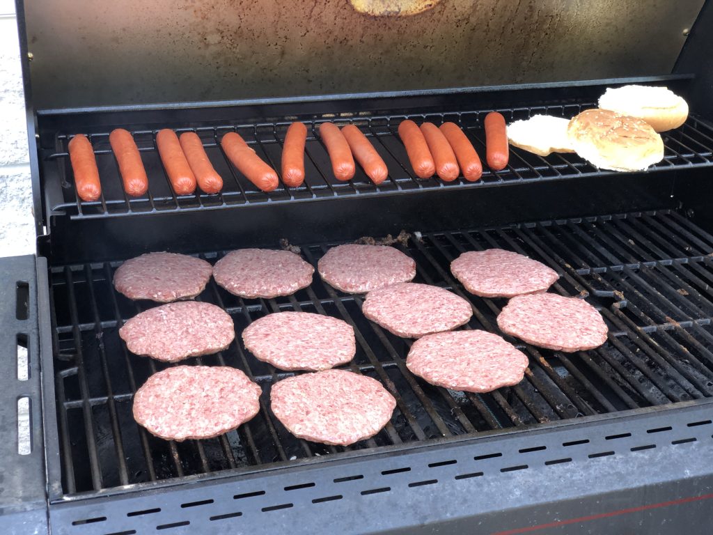 Buns à hamburger dorés posés sur une grille avec des galettes en cuisson