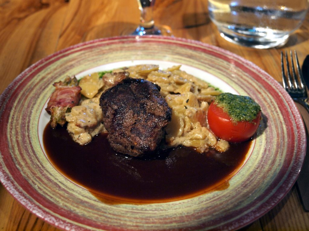 Pièce de viande rouge grillée servie avec un verre de vin rouge