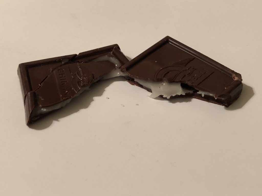 Morceaux de chocolat noir cassés révélant une cassure nette et brillante