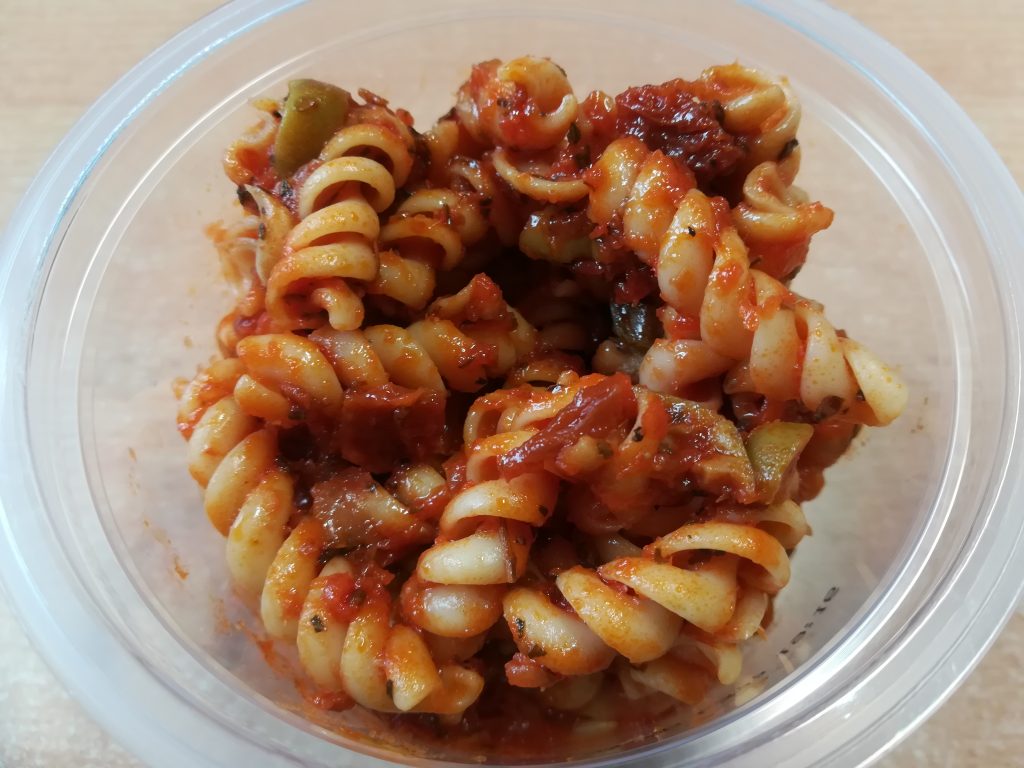 Salade de pâtes aux tomates séchées et olives vertes dans un saladier blanc