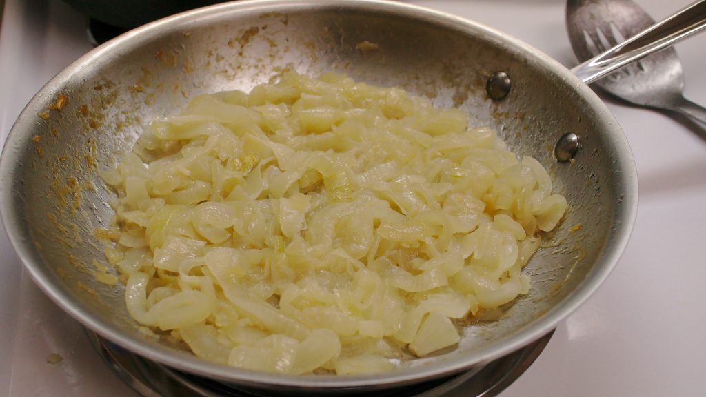 Oignons émincés en cours de caramélisation lente dans une cocotte