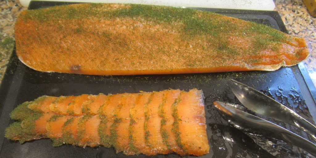 Tranches de saumon gravlax mariné à l'aneth disposées sur une planche